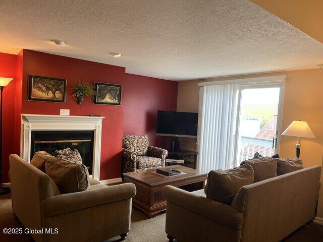 3014 Lake Shore Dr Unit 17D, Lake George, NY 12845 - living room with a textured ceiling, carpet, and a glass covered fireplace