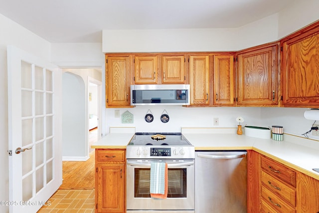 9 Arlene Ave, Guilderland, NY 12203 - kitchen with appliances with stainless steel finishes, light countertops, arched walkways, and brown cabinets