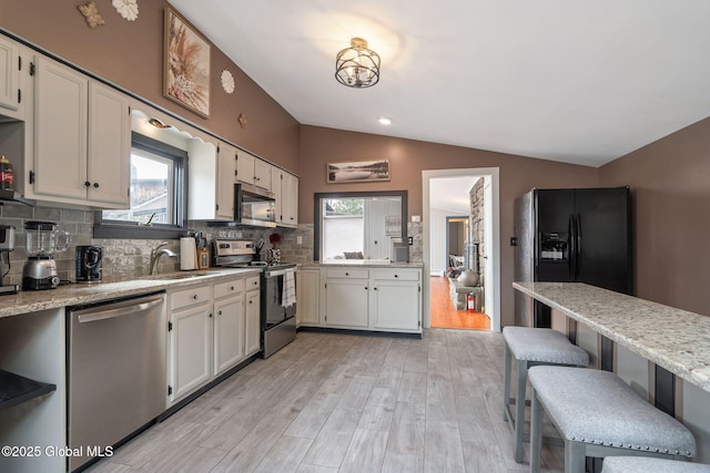 4A High Pines Ter, Warrensburg, NY 12817 - kitchen featuring appliances with stainless steel finishes, vaulted ceiling, backsplash, light wood-style floors, and a breakfast bar