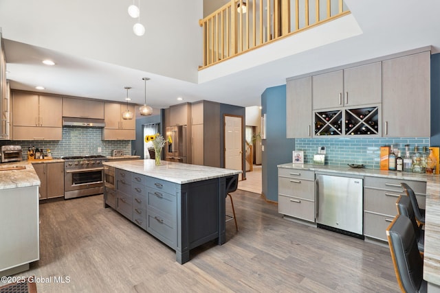 10 Overlook Dr, Wilton, NY 12831 - kitchen with high end appliances, under cabinet range hood, tasteful backsplash, gray cabinetry, and a high ceiling