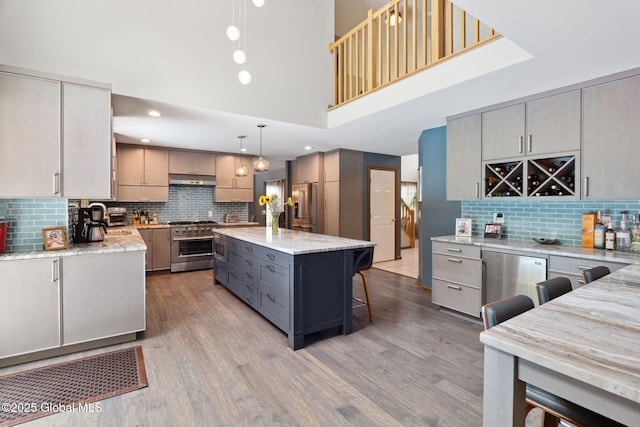 10 Overlook Dr, Wilton, NY 12831 - kitchen featuring premium appliances, gray cabinetry, decorative backsplash, a towering ceiling, and light stone counters
