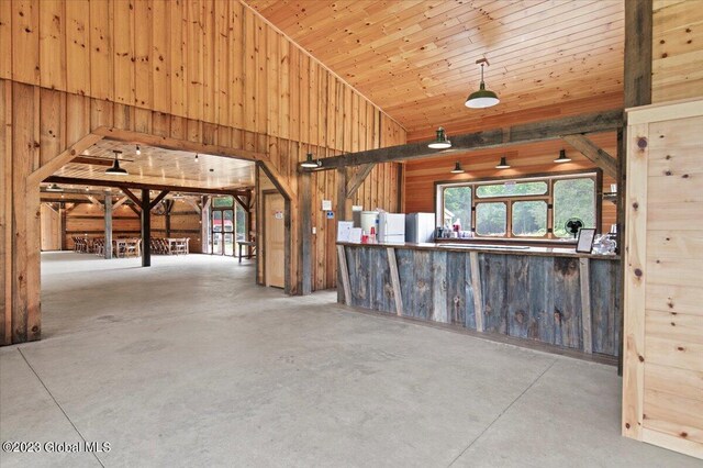 284 Edgemont Rd, Moriah, NY 12960 - interior space featuring wood walls, concrete floors, high vaulted ceiling, and freestanding refrigerator
