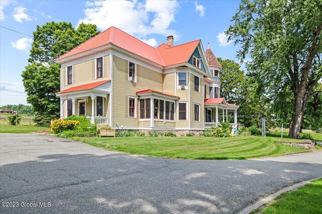 284 Edgemont Rd, Moriah, NY 12960 - victorian home featuring a chimney, a metal roof, covered porch, and a front lawn