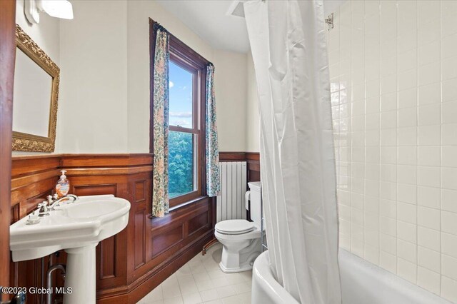 284 Edgemont Rd, Moriah, NY 12960 - bathroom featuring radiator heating unit, a wainscoted wall, and shower / bath combo with shower curtain