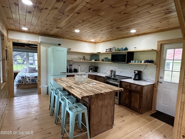 284 Edgemont Rd, Moriah, NY 12960 - kitchen with appliances with stainless steel finishes, open shelves, wood counters, a breakfast bar area, and plenty of natural light