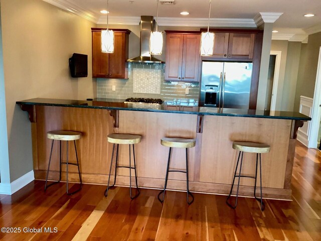 18 Division St Unit 515, Saratoga Springs, NY 12866 - kitchen featuring stainless steel fridge, wall chimney exhaust hood, crown molding, a kitchen bar, and dark wood-type flooring