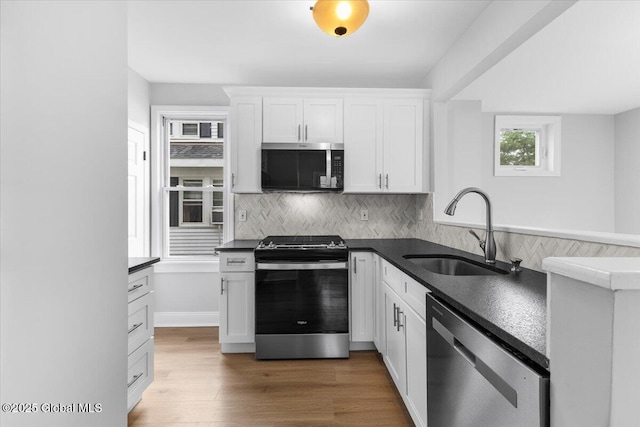 2321 1st Ave, Rotterdam, NY 12303 - kitchen featuring appliances with stainless steel finishes, dark countertops, white cabinets, backsplash, and wood finished floors