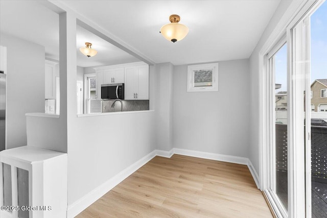 2321 1st Ave, Rotterdam, NY 12303 - kitchen with stainless steel microwave, light wood-style flooring, white cabinets, and light countertops
