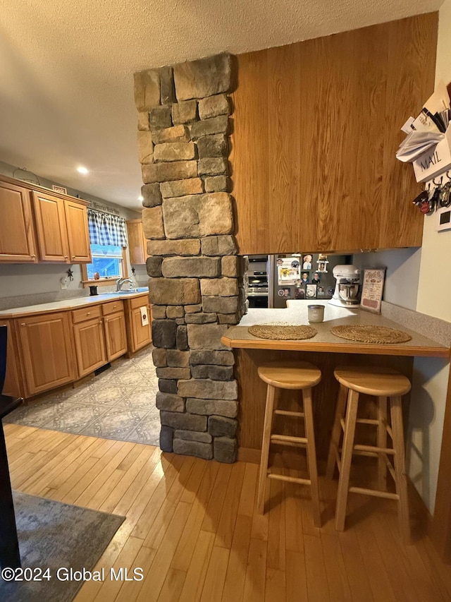 31 Wilson Ave, South Glens Falls, NY 12803 - kitchen with light wood-type flooring, a kitchen bar, light countertops, and a textured ceiling