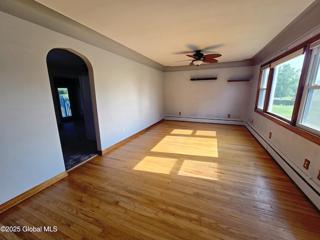1335 Midline Rd, Amsterdam, NY 12010 - unfurnished room featuring a ceiling fan, light wood-style floors, arched walkways, and a baseboard radiator