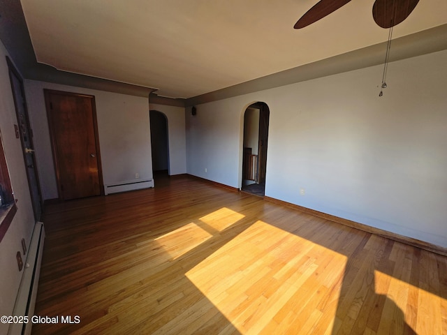 1335 Midline Rd, Amsterdam, NY 12010 - empty room with a baseboard heating unit, arched walkways, and wood finished floors
