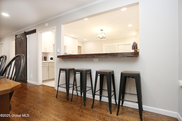 143 Maple Ave, Middleburgh, NY 12122 - kitchen featuring a kitchen bar, white cabinetry, wood finished floors, crown molding, and a barn door