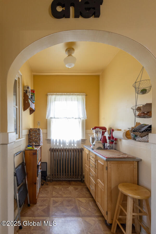 54 Wendell St, Ravena, NY 12143 - kitchen featuring radiator heating unit, arched walkways, light brown cabinetry, and a peninsula