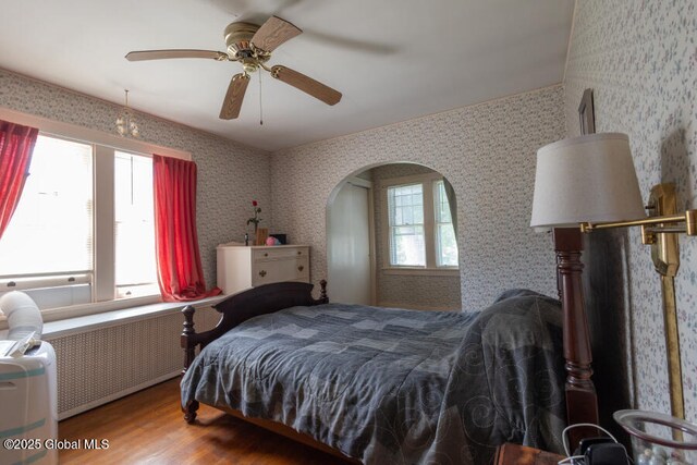 54 Wendell St, Ravena, NY 12143 - bedroom with radiator, wood finished floors, wallpapered walls, a ceiling fan, and arched walkways