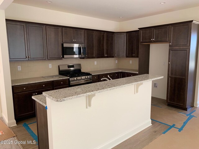 LOT17 Windrow Way, Halfmoon, NY 12118 - kitchen with stainless steel appliances, light wood-style floors, dark brown cabinets, an island with sink, and a kitchen breakfast bar