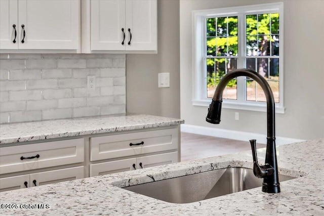 16 Surcingle Rd, Queensbury, NY 12804 - kitchen with backsplash, healthy amount of natural light, white cabinetry, and light stone countertops