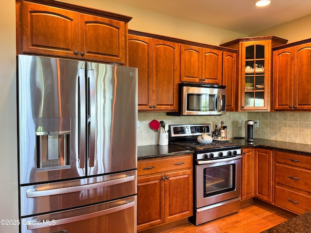 20 Beekman Pl, Queensbury, NY 12804 - kitchen with stainless steel appliances, dark stone counters, glass insert cabinets, light wood finished floors, and tasteful backsplash