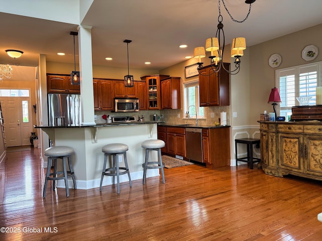 20 Beekman Pl, Queensbury, NY 12804 - kitchen featuring appliances with stainless steel finishes, a chandelier, a breakfast bar, wood finished floors, and dark countertops