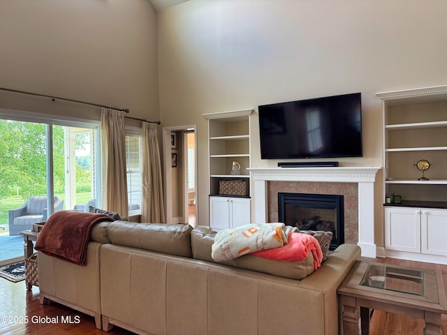 20 Beekman Pl, Queensbury, NY 12804 - living room featuring wood finished floors, a tiled fireplace, a towering ceiling, and built in features