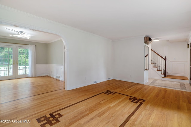11 Boylston Dr, Bethlehem, NY 12054 - unfurnished living room featuring a decorative wall, wood finished floors, stairs, wainscoting, and arched walkways