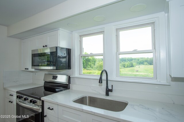 798 State Highway 29, Broadalbin, NY 12025 - kitchen with appliances with stainless steel finishes, white cabinetry, tasteful backsplash, and light stone countertops