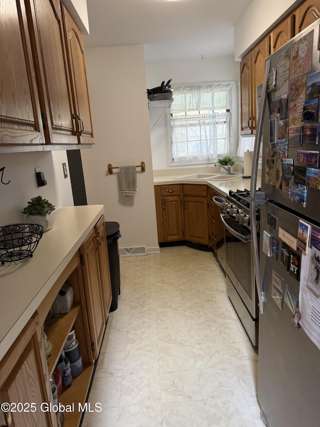7048 Suzanne Ln, Guilderland, NY 12303 - kitchen with stainless steel appliances, light countertops, brown cabinetry, and light flooring