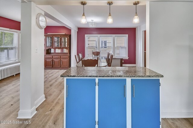 134 Whitehall Rd, Albany, NY 12209 - kitchen with blue cabinets, dark countertops, radiator, light wood-style flooring, and pendant lighting