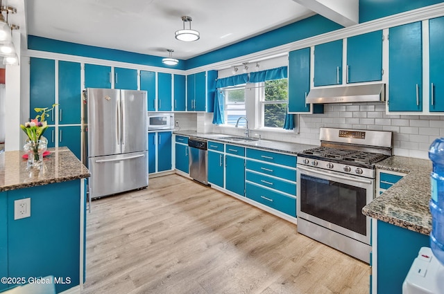 134 Whitehall Rd, Albany, NY 12209 - kitchen with appliances with stainless steel finishes, under cabinet range hood, blue cabinets, tasteful backsplash, and light wood-style floors