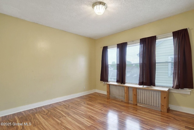 134 Whitehall Rd, Albany, NY 12209 - empty room with wood finished floors, radiator, and a textured ceiling