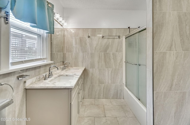 134 Whitehall Rd, Albany, NY 12209 - full bath featuring tile walls, double vanity, combined bath / shower with glass door, a textured ceiling, and tile patterned floors
