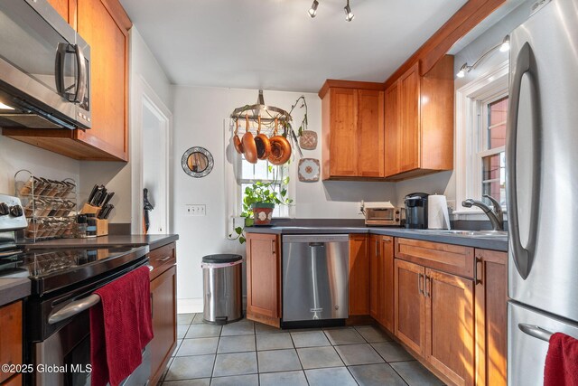 2305 Balltown Rd, Niskayuna, NY 12309 - kitchen with stainless steel appliances, dark countertops, light tile patterned floors, and brown cabinets