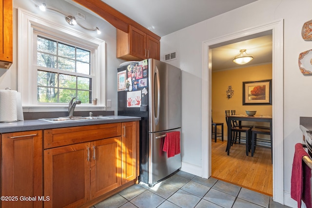 2305 Balltown Rd, Niskayuna, NY 12309 - kitchen featuring freestanding refrigerator, dark countertops, light tile patterned floors, brown cabinets, and ornamental molding