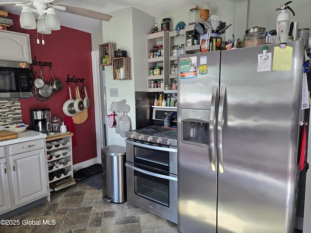 2922 Halsey Dr, Schenectady, NY 12304 - kitchen with stainless steel appliances, dark stone finish flooring, ceiling fan, decorative backsplash, and white cabinets