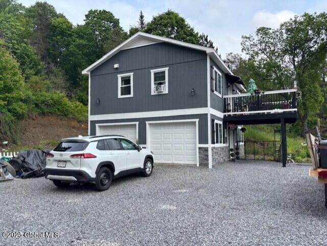 600 State Highway 309, Gloversville, NY 12078 - view of property exterior featuring a garage, a wooden deck, driveway, and stone siding