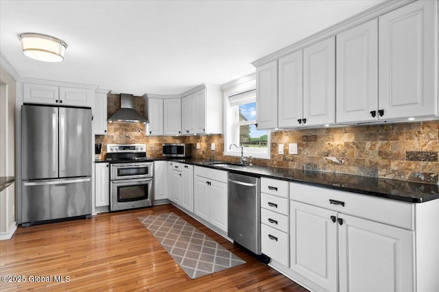 344 Fortsville Rd, Moreau, NY 12831 - kitchen with stainless steel appliances, wall chimney range hood, dark countertops, and light wood-type flooring
