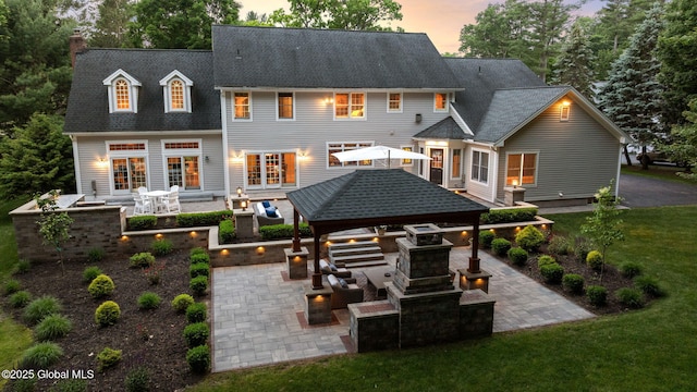 428 Ridgehill Rd, Guilderland, NY 12303 - back of house at dusk featuring a gazebo, a patio, an outdoor hangout area, and an outdoor kitchen