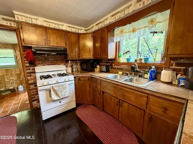 252 Main St, Hudson Falls, NY 12839 - kitchen featuring white gas range, under cabinet range hood, brown cabinetry, dark wood-style floors, and light countertops