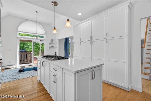 460 Grand Ave, Saratoga Springs, NY 12866 - kitchen with stainless steel gas stovetop, lofted ceiling, light wood-style floors, white cabinets, and a kitchen island