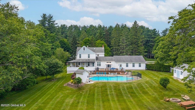 479 Loudon Rd, Colonie, NY 12211 - back of property with a fire pit, a wooden deck, a view of trees, a storage unit, and a yard