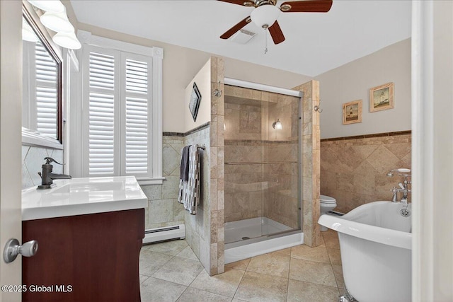 479 Loudon Rd, Colonie, NY 12211 - full bath with tile walls, a baseboard heating unit, a ceiling fan, tile patterned floors, and a freestanding bath