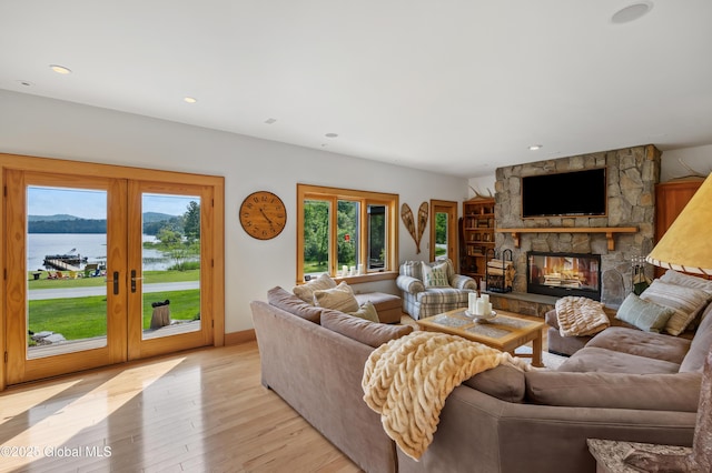 555 Trout Lake Rd, Bolton, NY 12824 - living area with french doors, light wood-style flooring, a stone fireplace, a water view, and recessed lighting
