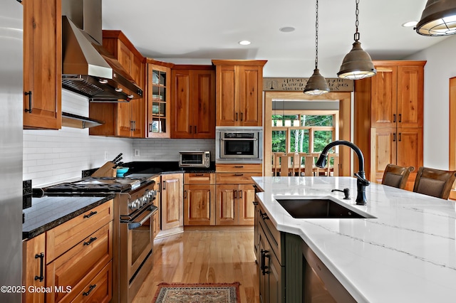 555 Trout Lake Rd, Bolton, NY 12824 - kitchen featuring wall chimney range hood, high end stove, light stone countertops, light wood-type flooring, and tasteful backsplash