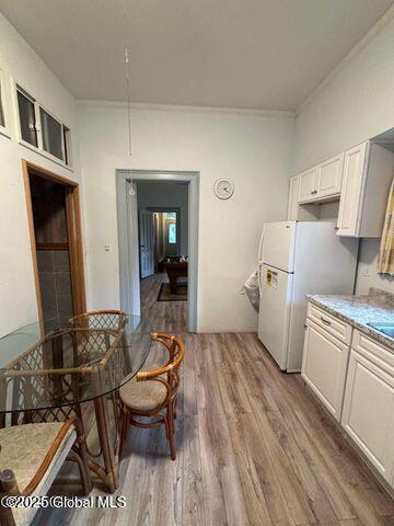 17 W St, Fort Plain, NY 13339 - kitchen with freestanding refrigerator, light wood-style floors, crown molding, light countertops, and white cabinets