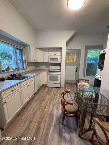 17 W St, Fort Plain, NY 13339 - kitchen featuring white appliances, stacked washing machine and dryer, light wood-style floors, and light countertops