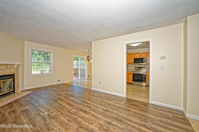 5 Bridgewood Ln, Watervliet, NY 12189 - unfurnished living room with light wood-style floors, a tile fireplace, and a chandelier