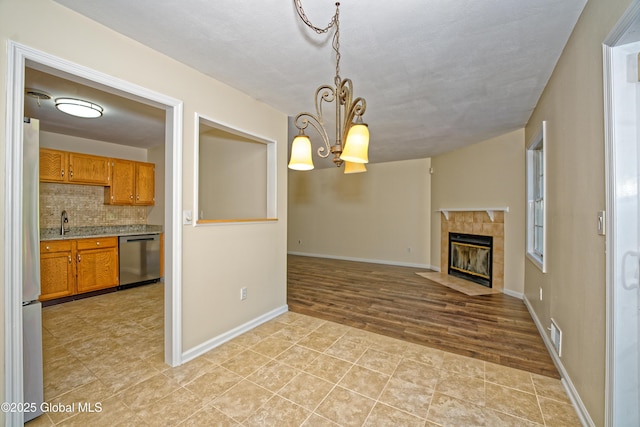 5 Bridgewood Ln, Watervliet, NY 12189 - unfurnished living room featuring a tiled fireplace, a chandelier, and light tile patterned flooring