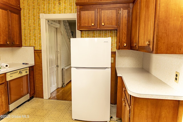 53 Broad St, Catskill, NY 12414 - kitchen with freestanding refrigerator, dishwasher, wallpapered walls, radiator heating unit, and brown cabinets