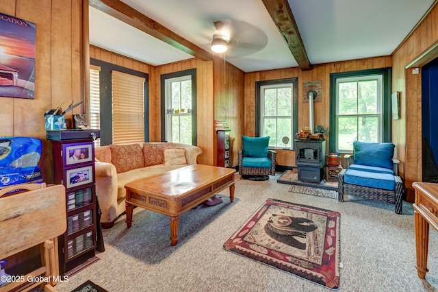 448 State Highway 334, Johnstown, NY 12095 - carpeted living room with a wood stove, wood walls, beamed ceiling, and ceiling fan