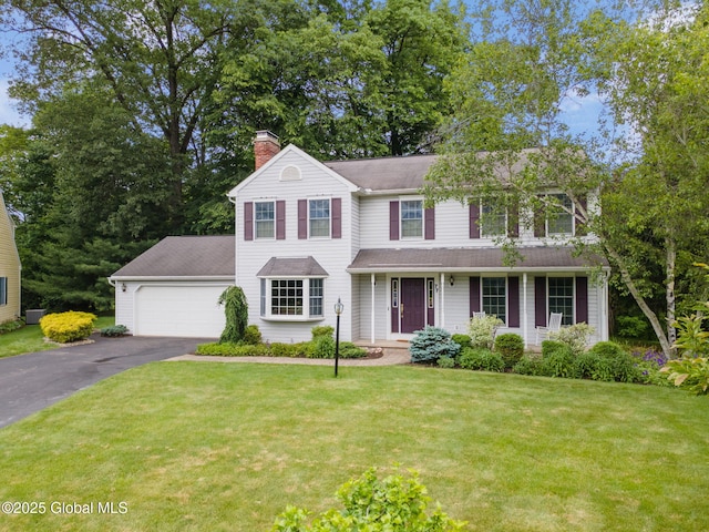 77 Rotterdam Dr, Bethlehem, NY 12077 - view of front facade featuring a chimney, asphalt driveway, a front yard, a garage, and a porch