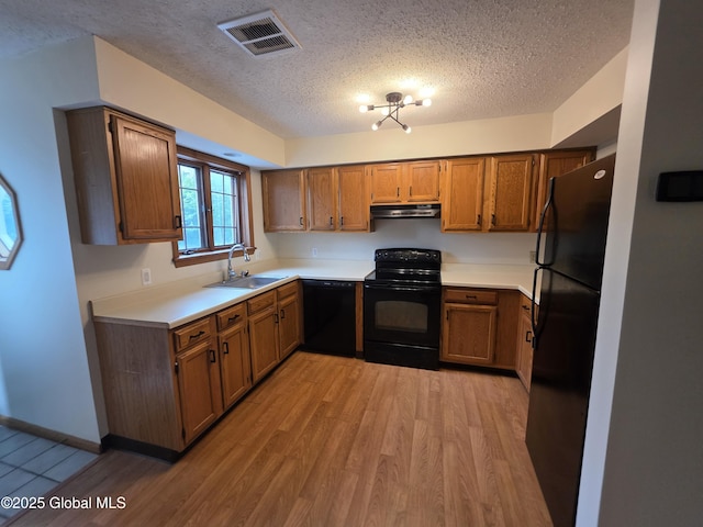 222 S Ten Broeck St Unit 26, Scotia, NY 12302 - kitchen featuring black appliances, under cabinet range hood, a textured ceiling, brown cabinetry, and light wood-style floors